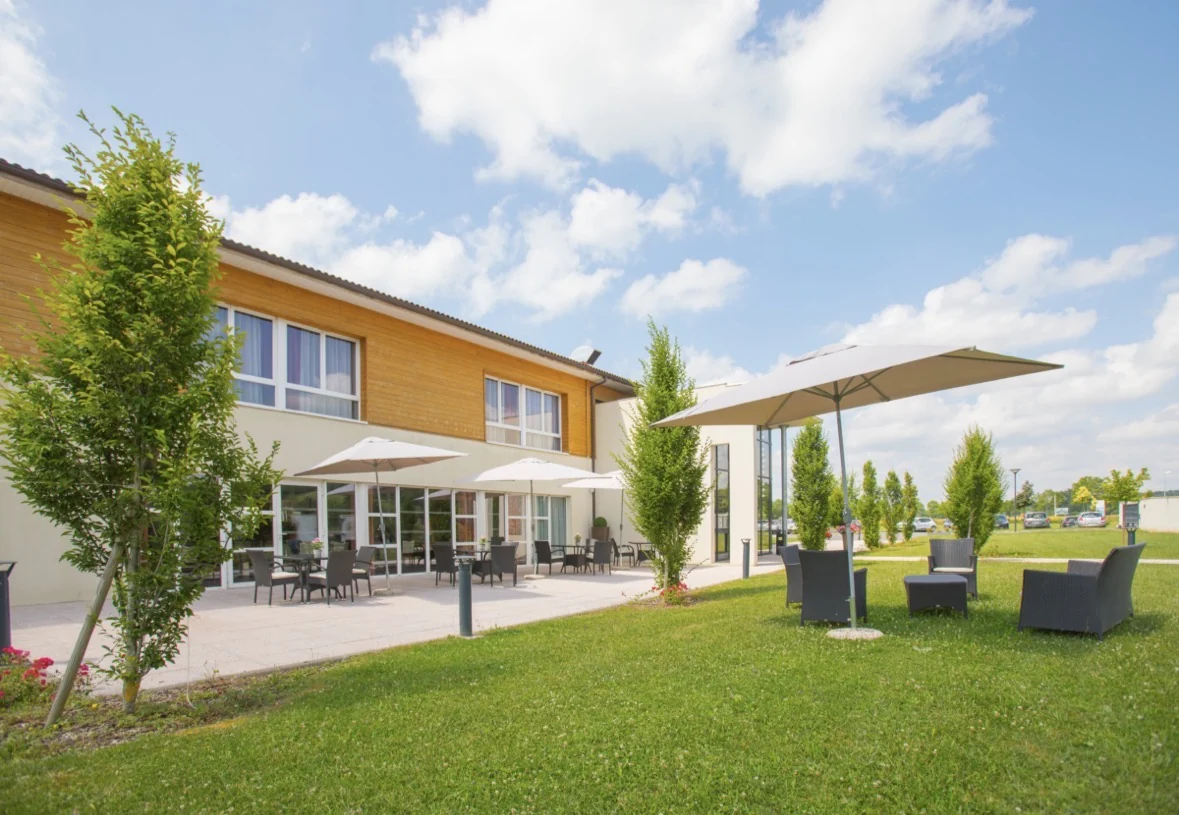 Façade d’un bâtiment et terrasse au milieu d’un jardin