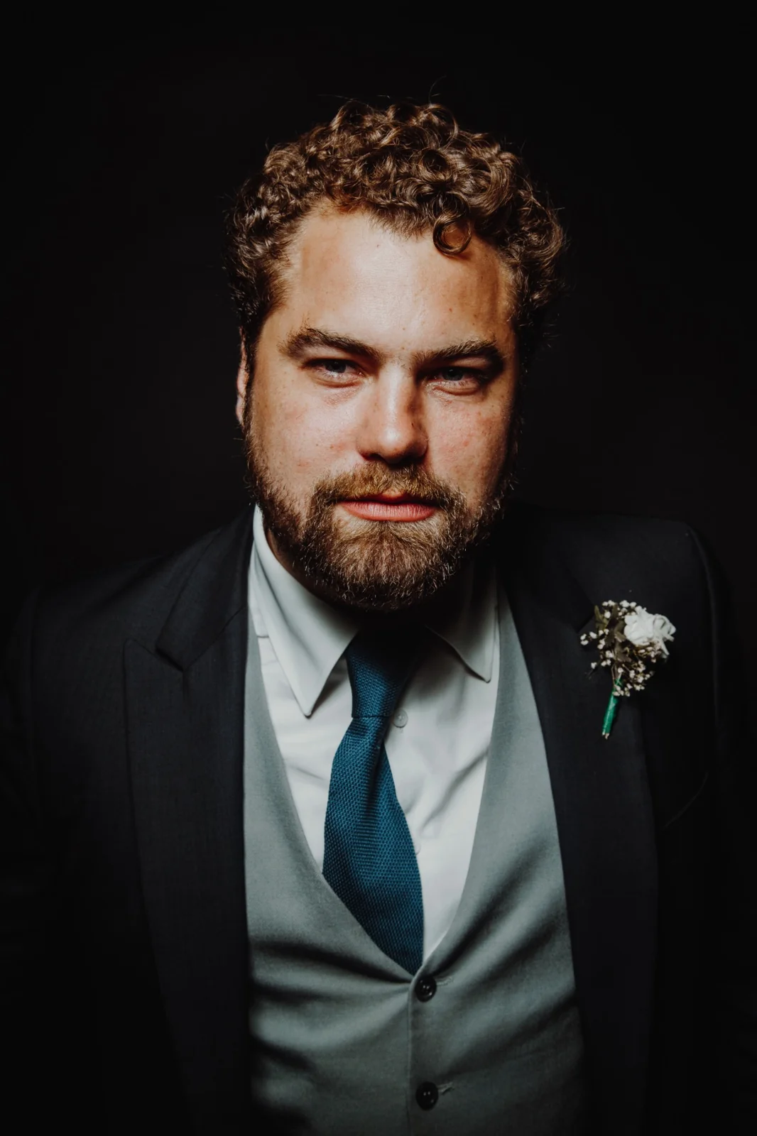 Portrait d’un homme barbu en costume et cravate sur fond sombre
