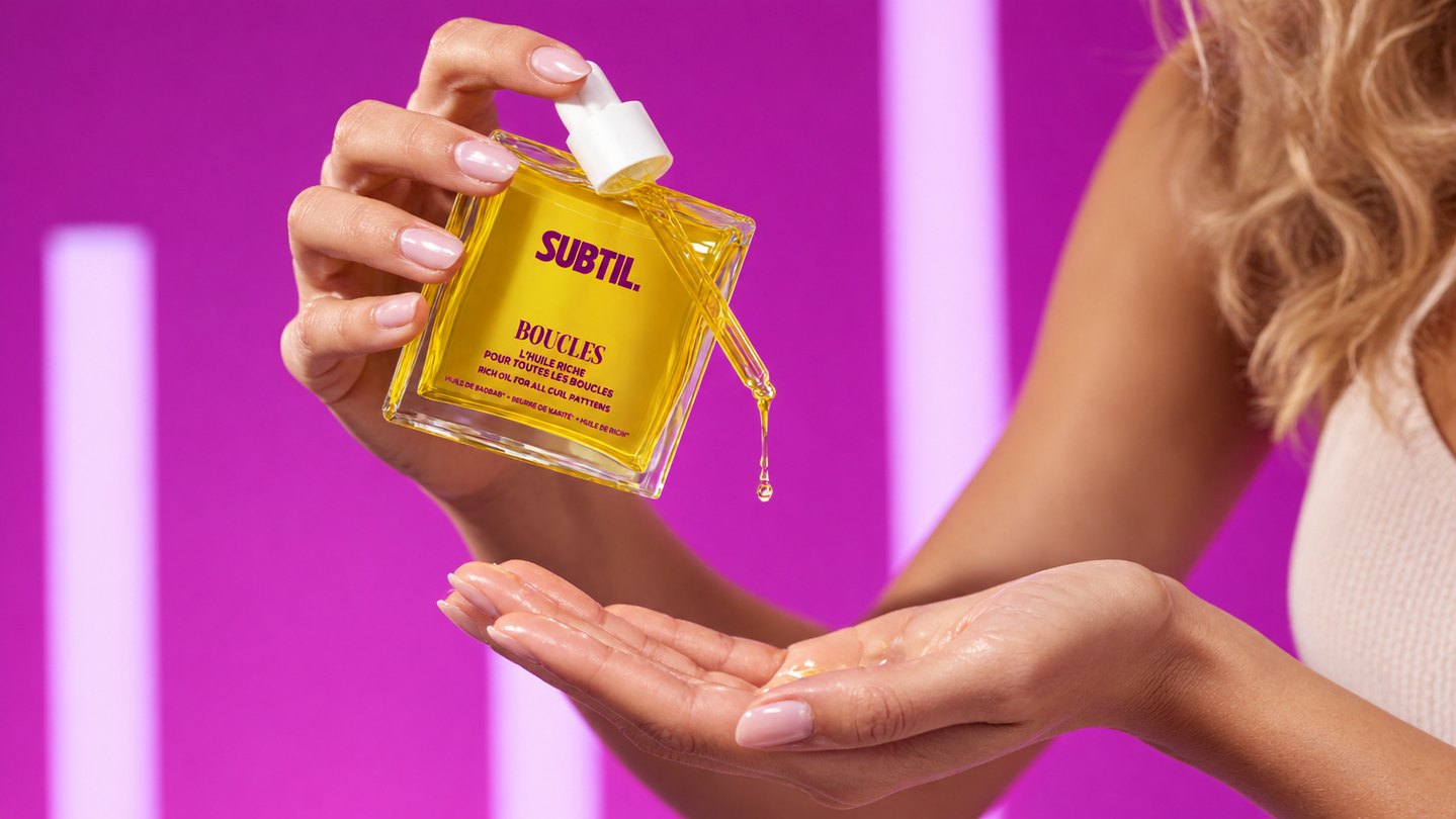Huile capillaire Subtil Boucles présentée en gros plan sur fond rose